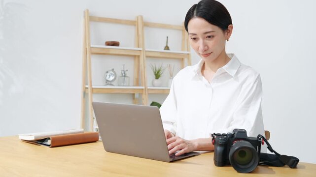 カメラとノートパソコンを使う女性。写真、編集、撮影、カメラマン、カメラ女子、現像、オークション、出品