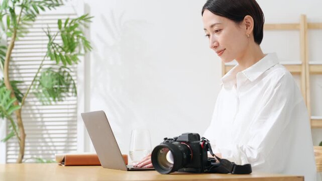カメラとノートパソコンを使う女性。写真、編集、撮影、カメラマン、カメラ女子、現像、オークション、出品
