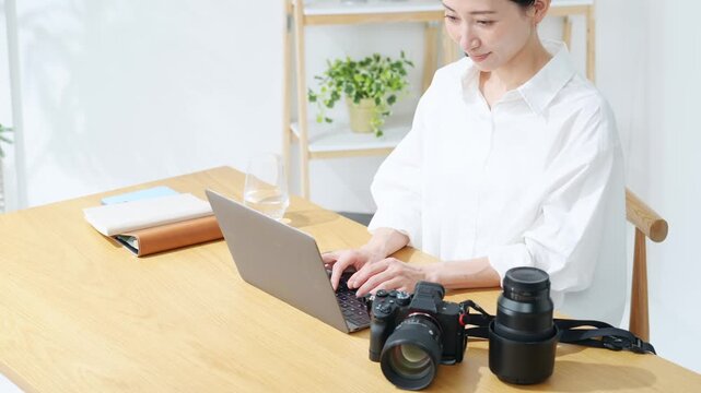 カメラとノートパソコンを使う女性。写真、編集、撮影、カメラマン、カメラ女子、現像、オークション、出品