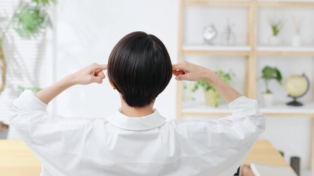 部屋で悩む女性の後ろ姿。仕事、家計簿、不安、心配、不満、疑問、考える、トラブル、問題、ストレス、疲労
