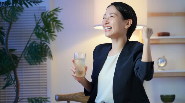 お酒を飲みながらガッツポーズする女性。スポーツバー、応援、飲み会、サポーター、興奮、試合、ゲーム