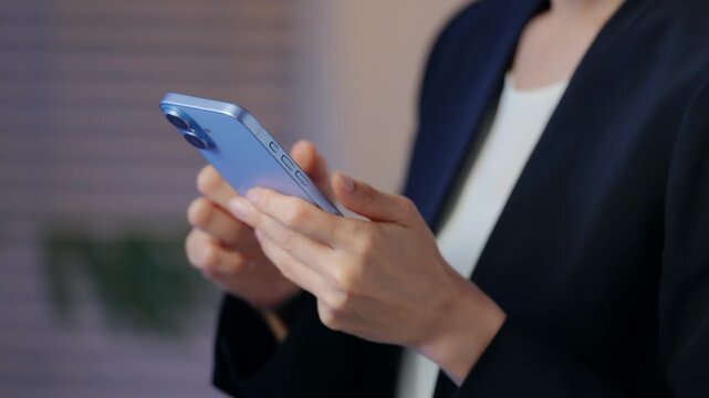 A woman looking at her smartphone in a dark room. Apps, social media, email, videos, DX, business, gaming, engrossed, searching, online shopping.
