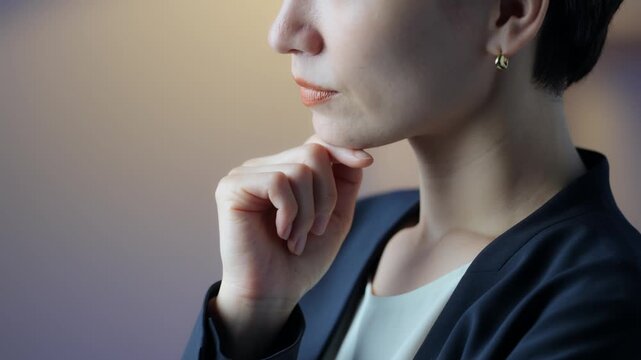 A middle-aged woman thinking in a dimly lit room. Serious, questioning, business owner, manager, decision-making, choices, worries, anxiety, concern, changing jobs, dissatisfaction.