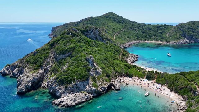 Kerkira, Corfu, Greece - 29 June 2026: Aerial view of Porto Timoni beach with turquoise waters, rocky cliffs, and lush greenery on a sunny day.