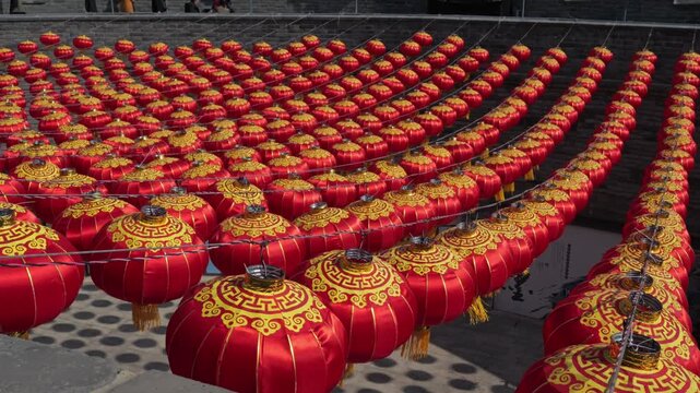 Rows of vibrant red Chinese lanterns hanging against an ancient brick wall background.