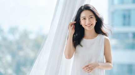 Fototapeta premium Portrait of a beautiful young asian woman smiling by a bright window