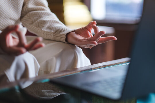 Closeup image of a woman hands in lotus pose over laptop computer for stress relief concept