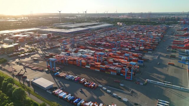 Hamburg, Germany - 01 July 2026: Aerial view of Container-Terminal-Altenwerder with rows of shipping containers and gantry cranes at sunset.