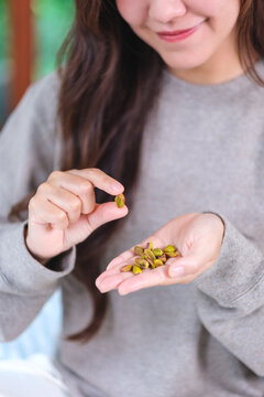 Vertical closeup image of a woman holding peeled pistachio nut