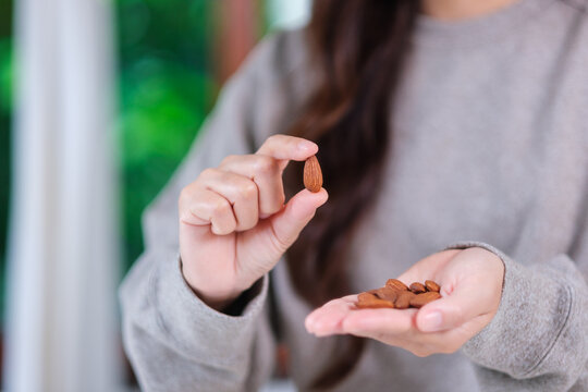 Closeup image of hands holding and picking up an almonds