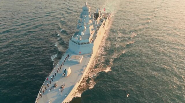 Istanbul, Turkey - 30 June 2026: Aerial view of a Turkish Navy frigate sailing through the Bosphorus strait at sunset with golden light reflecting on the water.
