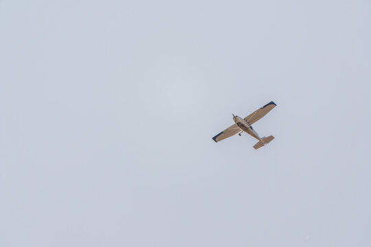 Small ultralight airplane with overhead wing and single propeller flying in sunset sky.