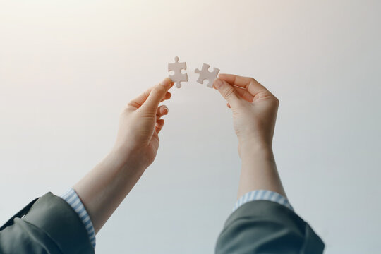 Business professional connecting puzzle pieces, symbolizing teamwork, partnership, problem solving, strategy, cooperation, and successful collaboration in business.