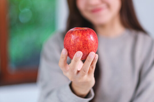 Closeup image of a woman holding and looking at a red apple
