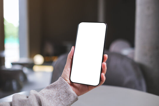 Mockup image of a woman holding mobile phone with blank desktop screen