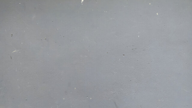 A closeup shot of a smooth, flat, light grey painted wall surface with subtle texture and minor imperfections, creating a minimalist industrial backdrop