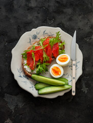 Delicious healthy breakfast - whole grain bread, salmon sandwich, boiled egg, fresh cucumber on a...