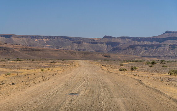 Desert road in Adrar Plateau, West Africa, in Mauritania landscape with sandstone rocks in the horizon, nearby Atar.
