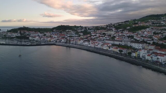 Horta Waterfront at sunset on Faial Island, Azores, Portugal, showing the harbour, buildings, moored yachts and warm evening light over the Atlantic Ocean, aerial