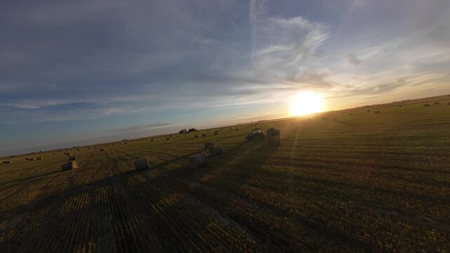 Rural work. Tractor with baler at sunset.