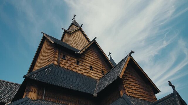 Low-angle view of a traditional Norwegian Heddal stave church with intricate wooden craftsmanship, steep roofs and dragon-head carvings. Timeless example of traditional Scandinavian craft