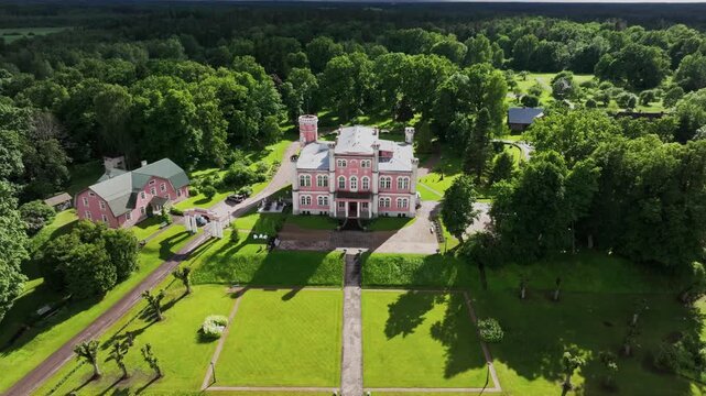 Drone footage of Birini Castle captured in dramatic evening light as dark thunderstorm clouds approach over the Latvian countryside. A cinematic aerial view combining historic architecture, formal gar