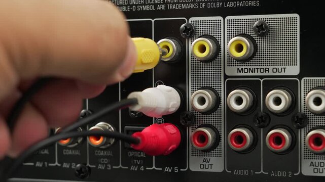 Male hand connects yellow and red RCA cables into the monitor out ports of an o video receiver, emphasizing analog connections and home entertainment setup.