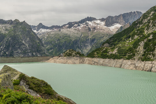 Guttannen, Switzerland. Gelmersee reservoir with exposed shoreline due to low water level and hydroelectric dam in the Bernese Alps