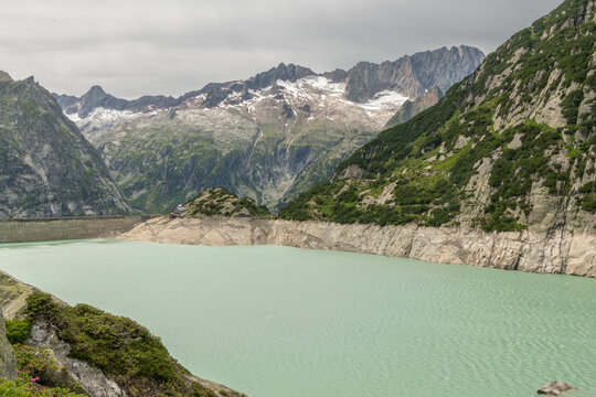 Guttannen, Switzerland. Gelmersee reservoir with hydroelectric dam, alpine mountains and low water level in the Bernese Alps