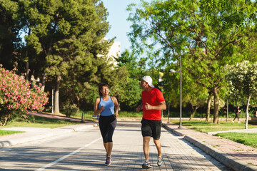 Obraz premium Senior couple running in park, smiling and exercising together for wellness