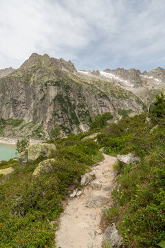 Guttannen, Switzerland. Alpine hiking trail overlooking Gelmersee reservoir and rugged mountain landscape in the Bernese Alps