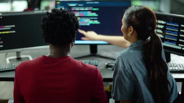 Male and Female Diverse IT professional collaborate on complex coding project in modern office. Programmers analyze data on multiple monitors, discussing software development and technology solutions