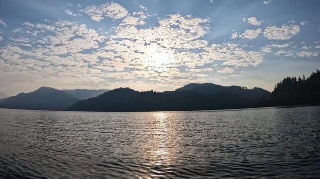 4K smooth stabilized action camera footage while kayaking on Yale Lake, Washington, USA with gentle waves, surrounding forested mountains and morning sunlight reflecting on the water during summer