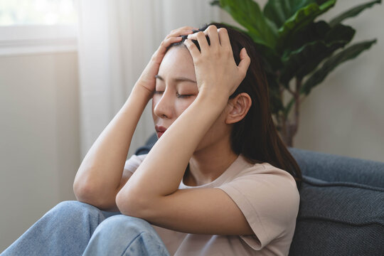 Asians female in stressed expression sitting on the sofa in the house.