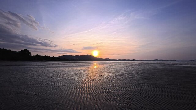 Golden sunset on a white sand tropical beach on a Thai island at low tide with reflections