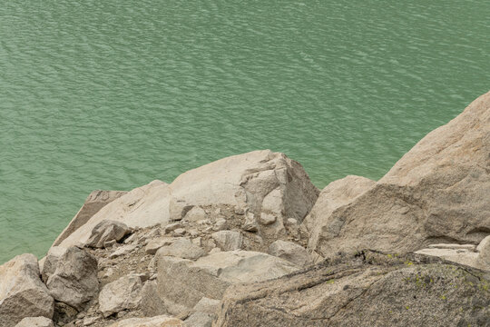 Guttannen, Switzerland. Granite boulders along the shoreline of Gelmersee reservoir with turquoise alpine water in the Bernese Alps