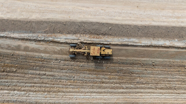 Aerial view motor grader civil at construction site, Motor grader work on construction site, Road grader on road construction site machine work on the construction of new road.
