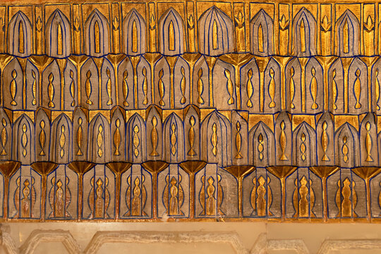 Gilded muqarnas ornament inside Gur-e-Amir mausoleum in Samarkand, Uzbekistan. Intricate gold and blue pointed arch patterns showcase Timurid architectural craftsmanship for heritage and design.