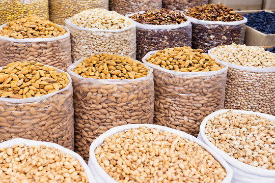 Bulk nuts and dried fruits displayed in large sacks at an oriental bazaar in Bukhara, Uzbekistan. Ideal for food industry, travel, and packaging design projects.