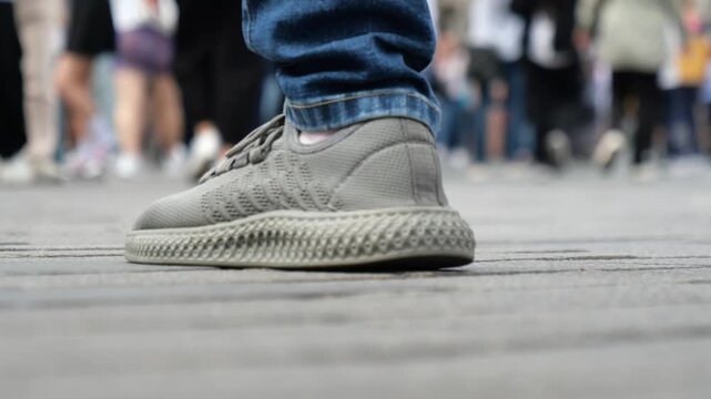 People walking on a stone paved street, low angle view of legs and feet in motion on a busy sidewalk