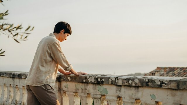 Man Reading Book by Sea View on Concrete Terrace at Sunset