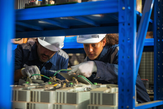 Industrial engineers inspecting electronic machinery, servo drives spare parts storehouse. Concept of second hand component recycling, technology hardware audit, maintenance, technical operations.