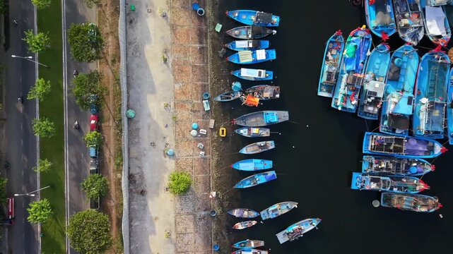 Smooth lateral drone shot of colorful fishing boats moored in Da Nang harbor during sunrise with calm water and soft morning light.