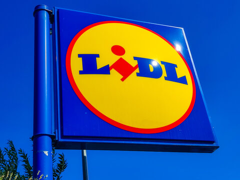 Ouistreham, France - July 08, 2026: Lidl supermarket sign with bright yellow background and blue lettering against clear blue sky