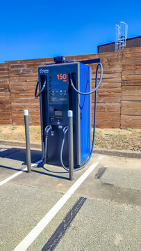 Sarge Les Le Mans, France - July 28, 2026: Electric vehicle charging station with 150 kW capacity in parking lot, wooden fence in background