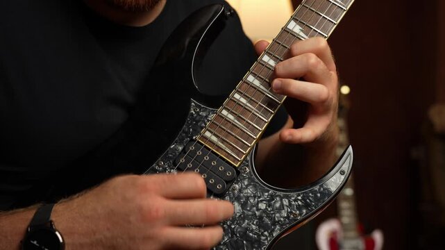 Young guy with ginger beard playing electrical guitar. Strumming and tapping and string picking.