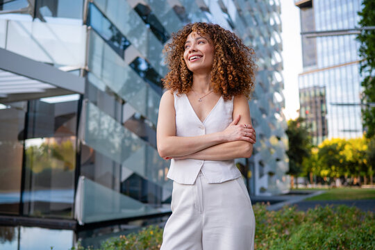 Confident businesswoman smiling with crossed arms in city