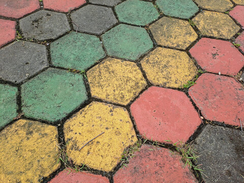 Textured red and green hexagonal stone pavers create a weathered pavement surface Abstract Background Concept Design