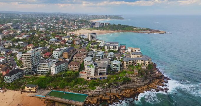 Aerial Manly Beach, Sydney, Australia, vibrant coastline with boutique residential buildings, sandy beach and an ocean pool. Beachfront apartments and modern homes line the shore of the Pacific Ocean