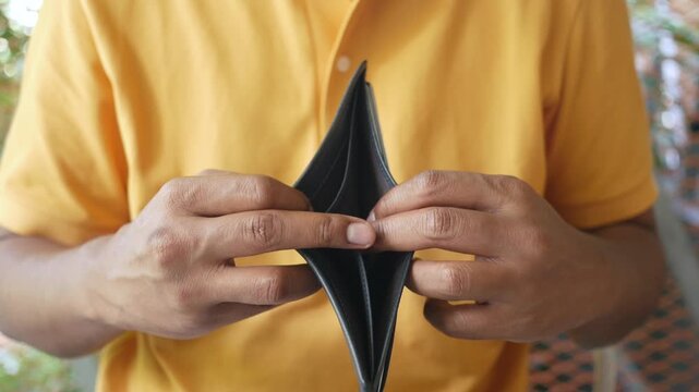 Man shows empty wallet with no money to spend and financial problems